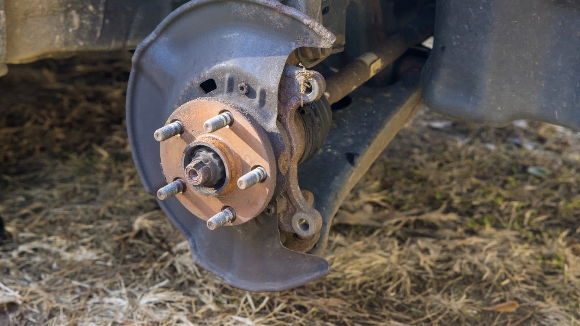 Exposed wheel hub and rusty rotor hat on a vehicle with the wheel removed